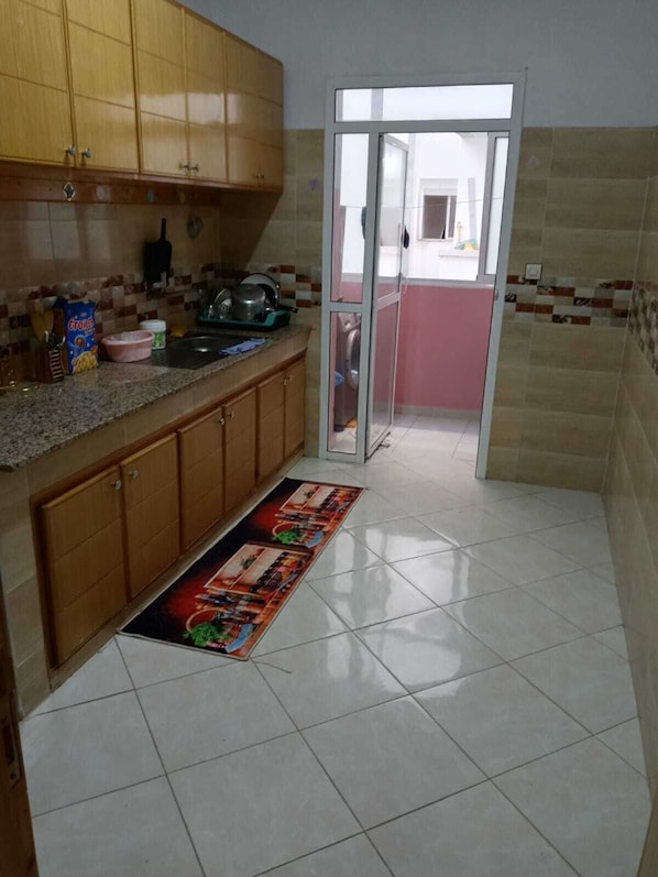 Une cuisine avec des meubles de rangement en bois, un pare-feu en carrelage, un Ă©vier et une fenĂȘtre.