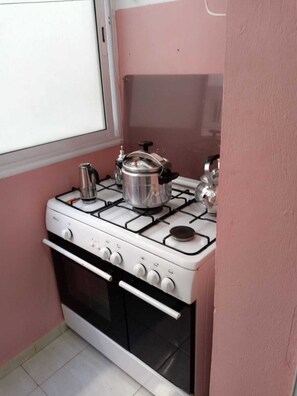 Une cuisine de taille réduite, équipée d’une cuisinière à gaz, d’un four et d’une petite fenêtre.