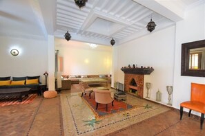 Un salon avec un canapé, des fauteuils, une cheminée et un téléviseur.