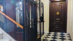 A staircase with a metal railing, a checkered floor, and a wooden door with a brass doorknob. - Charming Flat in the heart of Barcelona (Barcelona)