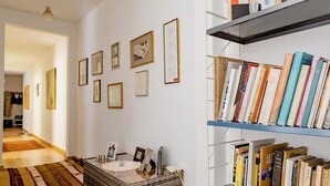 A room with a bookshelf, framed pictures on the wall, and a patterned rug. - Charming Flat in the heart of Barcelona (Barcelona)
