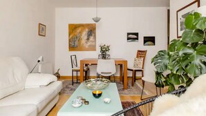A living room with a sofa, dining table, chairs, a coffee table, and a large plant. - Charming Flat in the heart of Barcelona (Barcelona)