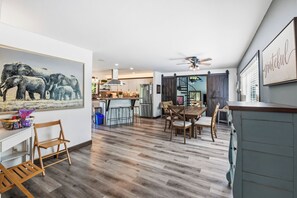 A spacious kitchen with a dining area, a ceiling fan, and a large painting of elephants.