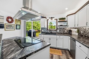 A modern kitchen with white cabinets, a black countertop, and a built-in stove.