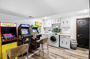 Un lavadero con lavadoras, una secadora y dos juegos de arcade.