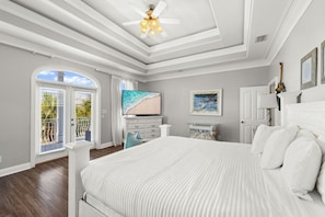 Ein Schlafzimmer mit einem großen Bett, einem Fernseher, einem Gemälde und einem Deckenventilator.