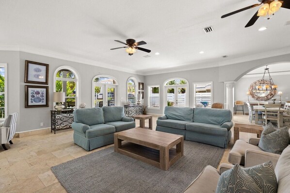 A spacious living room with two sofas, a coffee table, and a ceiling fan. - NEW! Family Fun By the Beach|Oceanview|Heated Pool|Walk to Beach (Destin)
