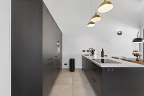 A modern kitchen with dark cabinetry, a central island, and pendant lighting.