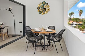 A dining area with a round table, black chairs, and a decorative wall piece.