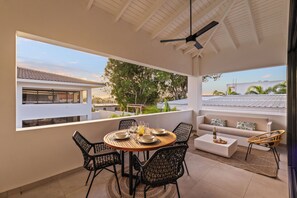 A sunlit patio with a round table set for dining, a sofa, and a ceiling fan.