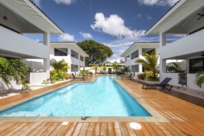 A modern hotel with a central swimming pool, multiple balconies, and tropical landscaping. - Curadise Penthouse - luxury poolside apartment in Jan Thiel (Jan Thiel)