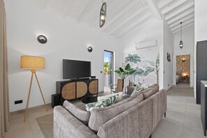 A modern living room with a sofa, television, and a plant. - Curadise Penthouse - luxury poolside apartment in Jan Thiel (Jan Thiel)