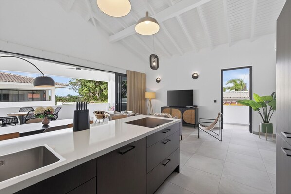 A modern kitchen with a large island, built-in appliances, and a dining area with outdoor seating. - Curadise Penthouse - luxury poolside apartment in Jan Thiel (Jan Thiel)