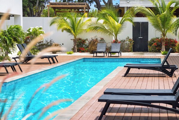 Une piscine dotée de chaises longues et agrémentée de plantes tropicales.