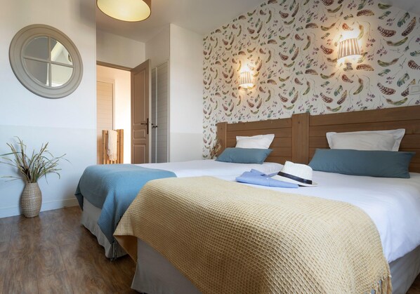 Habitación de hotel con una cama grande, una lámpara de noche, un espejo y un papel tapiz floral.