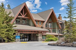 A lodge with a stone facade, multiple windows, and a prominent entrance. - Comfy 1-bedroom condo with AC in Magical Canmore (Canmore)