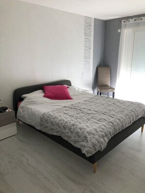 A modern bedroom with a bed, a chair, and a window with blinds. - Beautiful house with swimming pool 5 minutes from the 24 Hours of Le Mans racetrack (Ruaudin)