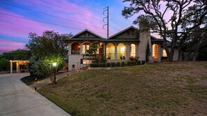 A two-story house with a covered porch, a front yard, and a driveway. - Luxury Pool, Hot Tub, Pickleball, Family Resort Getaway! (San Antonio)