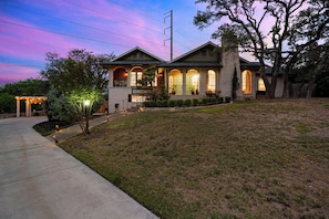 A two-story house with a covered porch, a front yard, and a driveway.