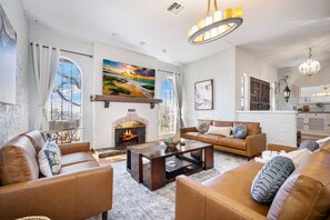 A living room with leather sofas, a fireplace, and a large painting of a beach scene.