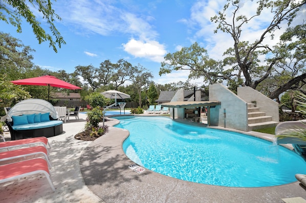 A swimming pool with lounge chairs and a covered seating area.