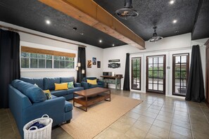 A living room with a blue sofa, wooden coffee table, and a large window with blinds.