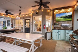 A kitchen with a large TV, wooden cabinets, and a dining area with a table and benches.