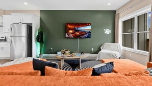 A modern living room with a flat-screen TV, a sofa, a coffee table, and a dining area. - Music City House, Sleeps 12 and Very close to Broadway, DT (Nashville)