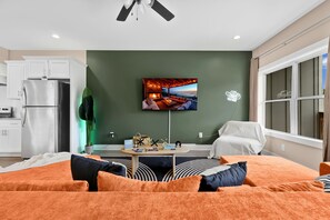 A modern living room with a flat-screen TV, a sofa, a coffee table, and a dining area.
