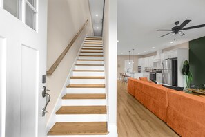 Eine Treppe führt zu einer modernen Küche mit Deckenventilator und Holzboden.