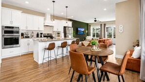 A modern kitchen with white cabinets, stainless steel appliances, and a central island with bar stools. - Music City House, Sleeps 12 and Very close to Broadway, DT (Nashville)