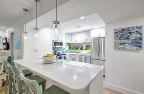 A modern kitchen with white cabinets, stainless steel appliances, and pendant lighting. - Your tropical oasis awaits your arrival in siesta key. (Siesta Key)