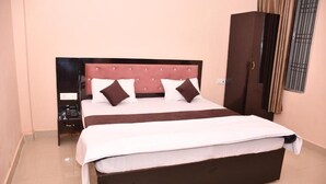 Quarto com cama grande, mesa de cabeceira, guarda-roupa e janela com grades.