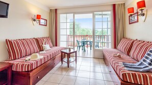 A room with two striped sofas, a small table, and a balcony with chairs. - Picturesque Old Aquitaine Apartment for 5 (Biscarrosse)