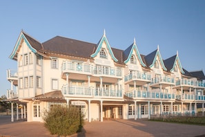 A multi-story hotel with balconies, a covered entrance, and a sign indicating it is a hotel. - House With Terrace Overlooking the Lake (Fort-Mahon-Plage)