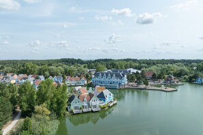 Ein Dorf am Seeufer mit Häusern am Wasser, einem Steg und einem Weg zum See.