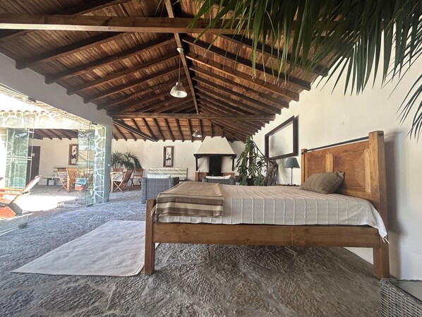 Ein Bett mit hölzernem Kopfteil, eine Pendelleuchte und ein Steinboden.