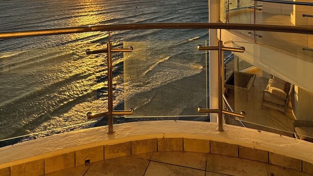 A balcony with a view of the ocean and a sunset. - Sky Beachfront Escape, 180 degree ocean view, 15th floor (Cape Town)