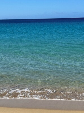A beach with clear water and a sandy shore.