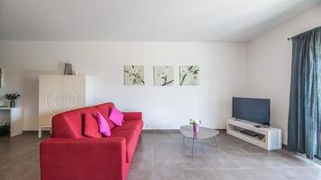 A modern living room with a red sofa, a flat-screen TV, and artwork on the wall.