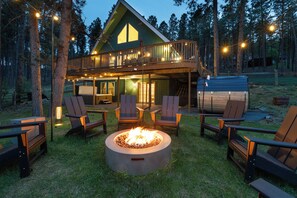 Eine Holzhütte mit Feuerstelle, Sitzgelegenheiten im Freien und einer Terrasse.