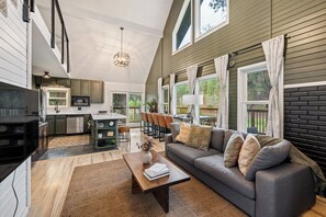 A spacious living area with a sofa, coffee table, and a kitchen in the background. - Black Hills Retreat Sauna/Hot Tub 5 min to Pactola (Rapid City)