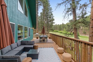Une terrasse avec un canapé, une table et des chaises, entourée d’arbres.