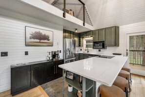 A modern kitchen with a large island, stainless steel appliances, and a view of the outdoors. - Black Hills Retreat Sauna/Hot Tub 5 min to Pactola (Rapid City)
