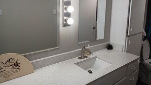 Une salle de bain avec un lavabo, un miroir et un meuble-lavabo.