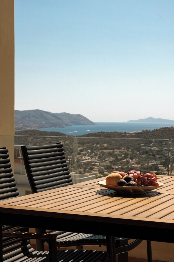 A balcony with a table set for a meal, overlooking a scenic landscape with mountains and a body of water. - Modern Sea View Apartment with Balcony on the Athenian Riviera (Anavissos)