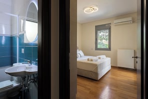 A hotel room with a bathroom, a bed, a window, and a radiator. - Modern Sea View Apartment with Balcony on the Athenian Riviera (Anavissos)