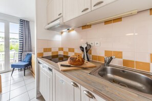 Eine moderne Küche mit Brot auf einem Schneidebrett, einer Spüle und einem Stuhl am Fenster.