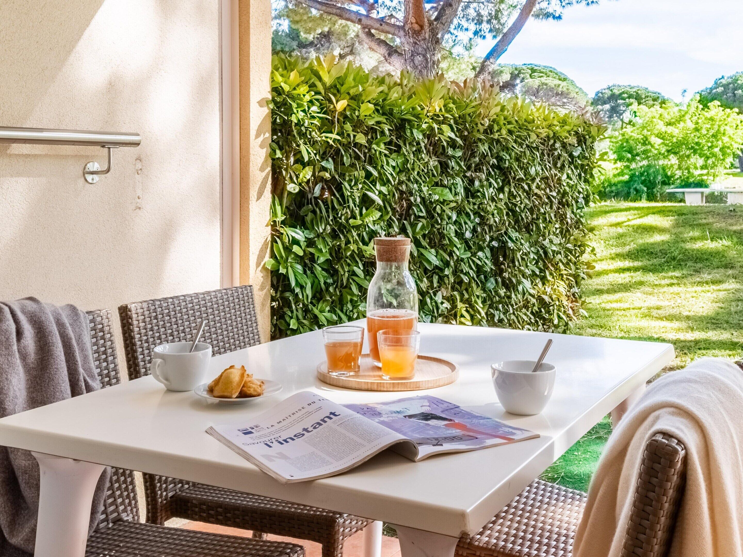 Een tafel met een krant, een glas jus d'orange, een fles en een bord met croissants.