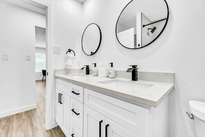 A modern bathroom with two sinks, white cabinetry, and round mirrors. - New! Walk to FIFA 2026 Football Games Dallas /AT&T Stadium! TX LIVE! Globe Life (Arlington)
